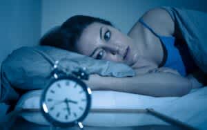 woman wide awake looking at alarm clock because of reasons you cant sleep