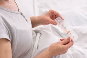 Senior woman taking medication from a pill box in bed