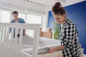 Young couple putting new mattress on bed