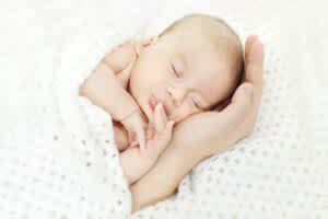 stock photo of a parent supporting a baby's head while they sleep