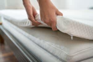 stock photo of a person adjusting a mattress topper