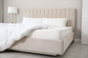 stock photo of an large mattress on a beige bed frame