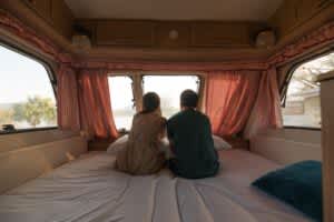 stock image of a couple sitting on a mattress in an rv