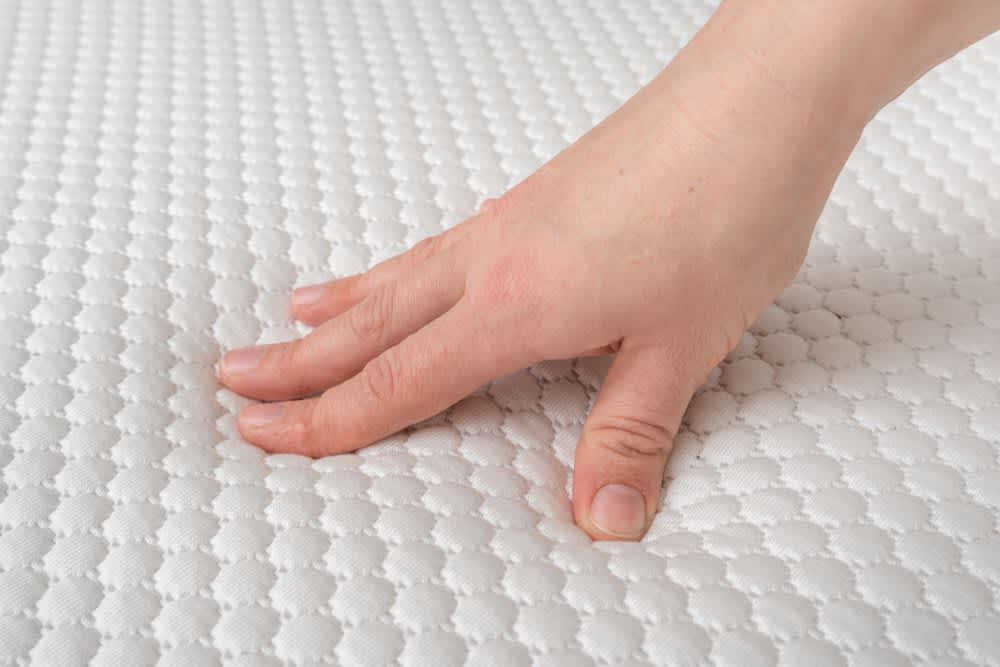 stock photo of a woman pressing her hand into a mattress
