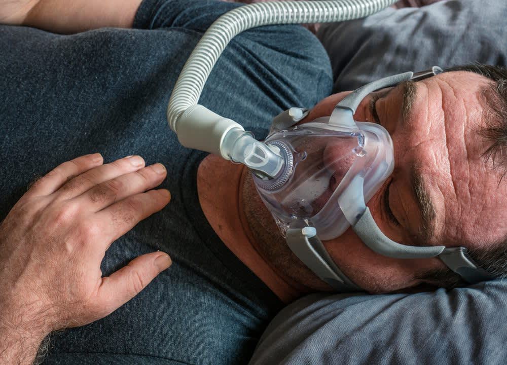 stock photo of a man sleeping with a cpap mask