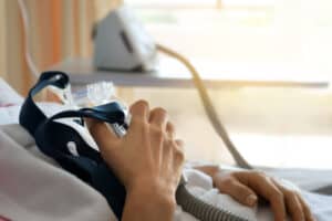 Closeup of a senior patient holding a cpap mask to his chest