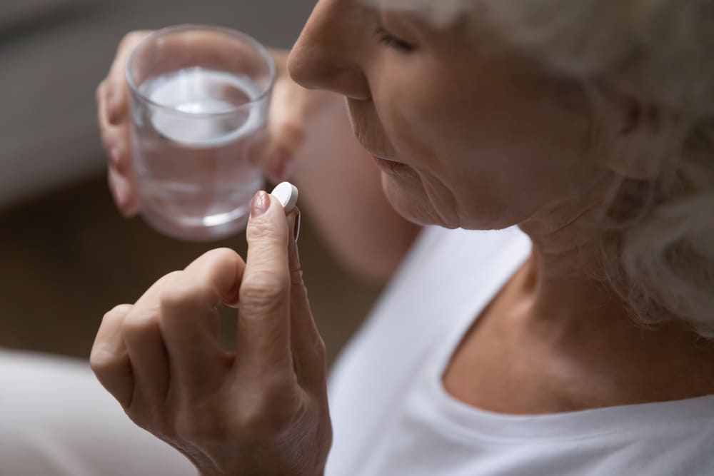 Top above view middle aged retired woman holding a pill