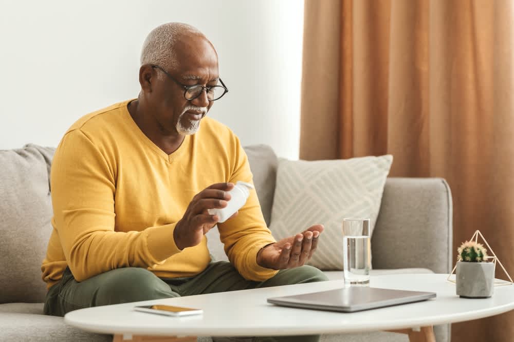 Mature black man putting pill in hand