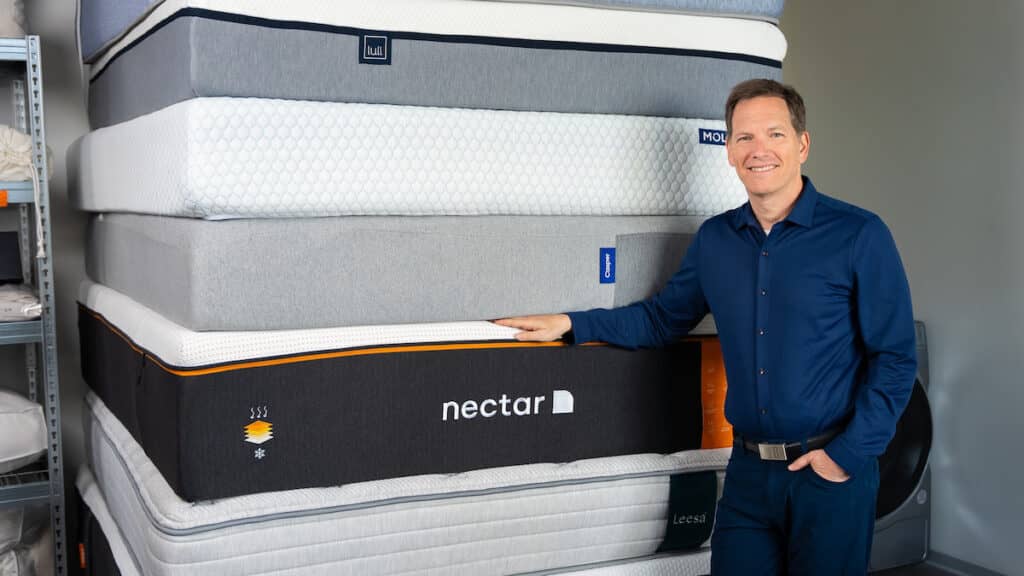 Dr. Michael Breus with a stack of mattresses in testing lab